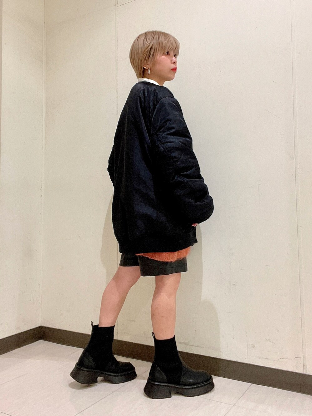 ブラック系のMA-1、オレンジ系のカーディガン/ボレロ、ホワイト系のTシャツ/カットソーを着用したレディースの冬コーディネートの3枚目の写真