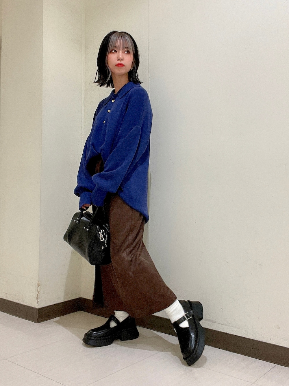 ブルー系のニット/セーター、ブラウン系のスカート、ブラック系のボストンバッグを着用したレディースの秋コーディネートの3枚目の写真