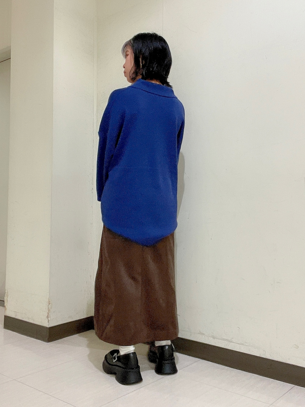 ブルー系のニット/セーター、ブラウン系のスカート、ブラック系のボストンバッグを着用したレディースの秋コーディネートの4枚目の写真