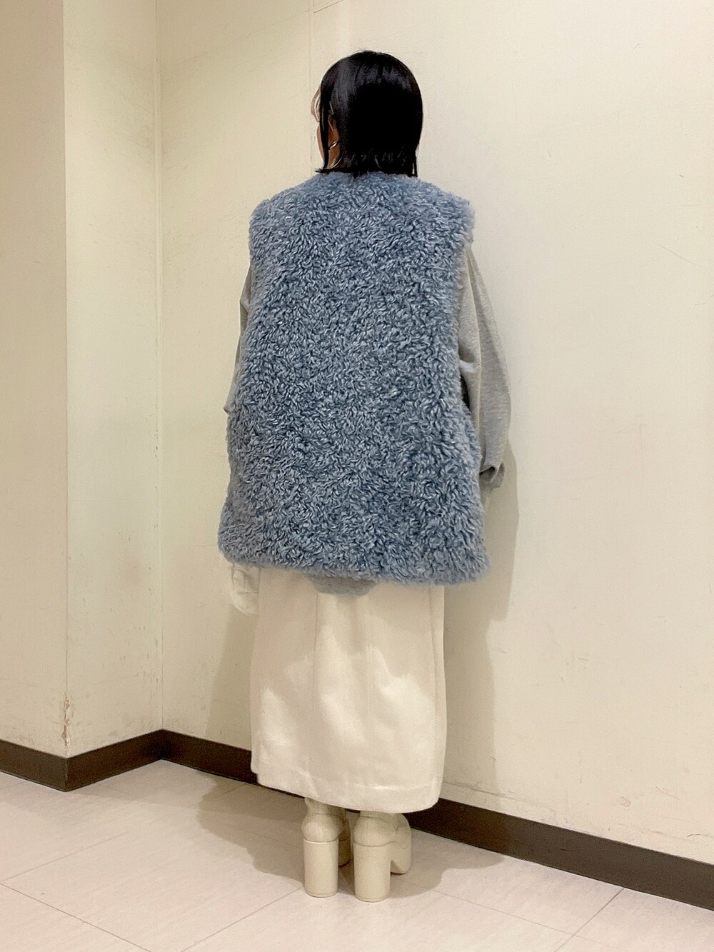 ホワイト系のショルダーバッグ、ブルー系のベスト、グレー系のスウェットを着用したレディースの秋コーディネートの2枚目の写真