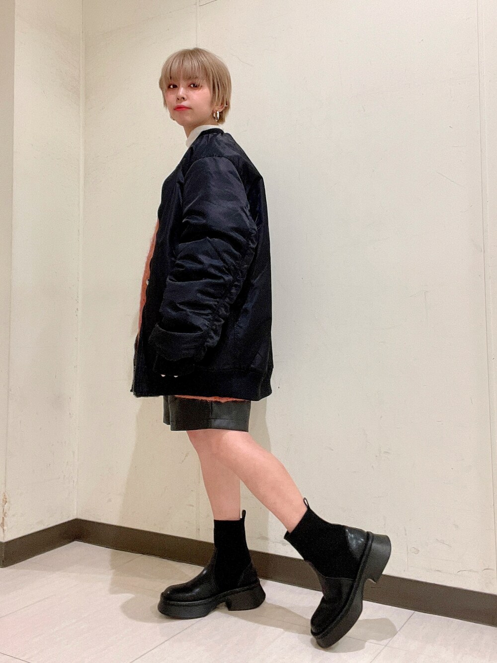 ブラック系のMA-1、オレンジ系のカーディガン/ボレロ、ホワイト系のTシャツ/カットソーを着用したレディースの冬コーディネートの5枚目の写真