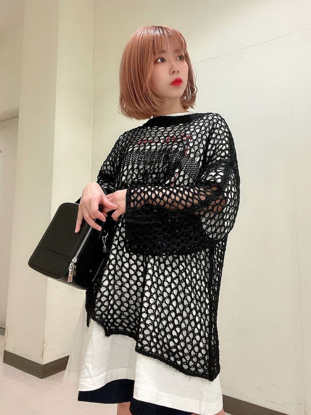 ホワイト系のTシャツ/カットソー、ブラック系のショルダーバッグ、ブラック系のニット/セーターを着用したレディースの春コーディネートの5枚目の写真