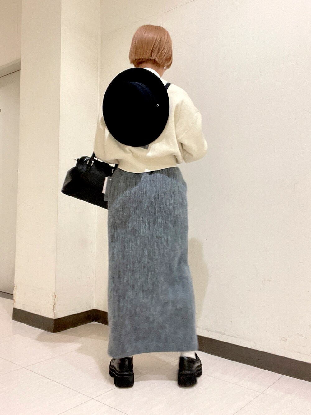 ホワイト系のカーディガン/ボレロ、ブルー系のスカート、ブラック系のパンプスを着用したレディースの冬コーディネートの2枚目の写真