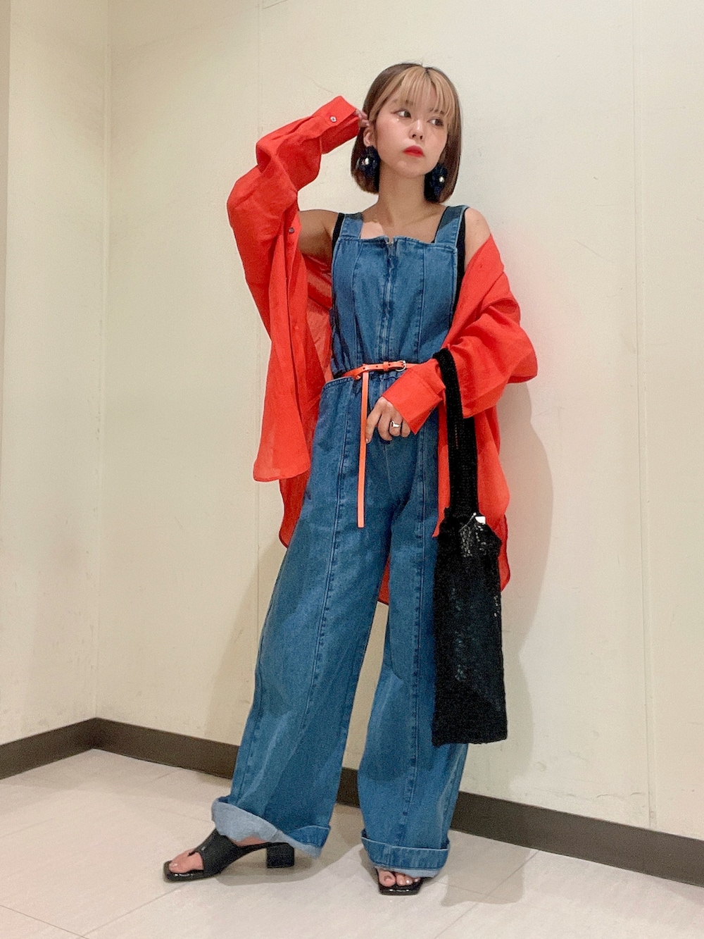 ブルー系のサロペット/オーバーオール、オレンジ系のシャツ/ブラウス、ブラック系のニット/セーターを着用したレディースの夏コーディネートの2枚目の写真