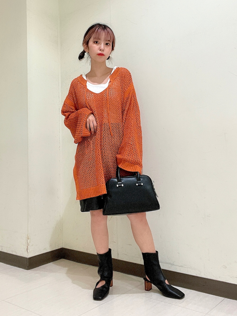 ブラック系のボストンバッグ、ブラック系のブーツ、オレンジ系のニット/セーターを着用したレディースの夏コーディネートの2枚目の写真