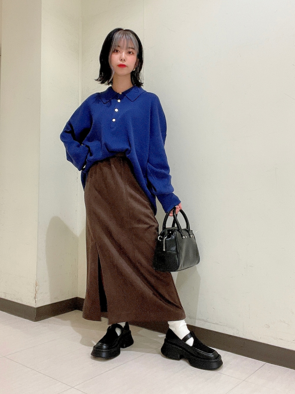 ブルー系のニット/セーター、ブラウン系のスカート、ブラック系のボストンバッグを着用したレディースの秋コーディネートの2枚目の写真