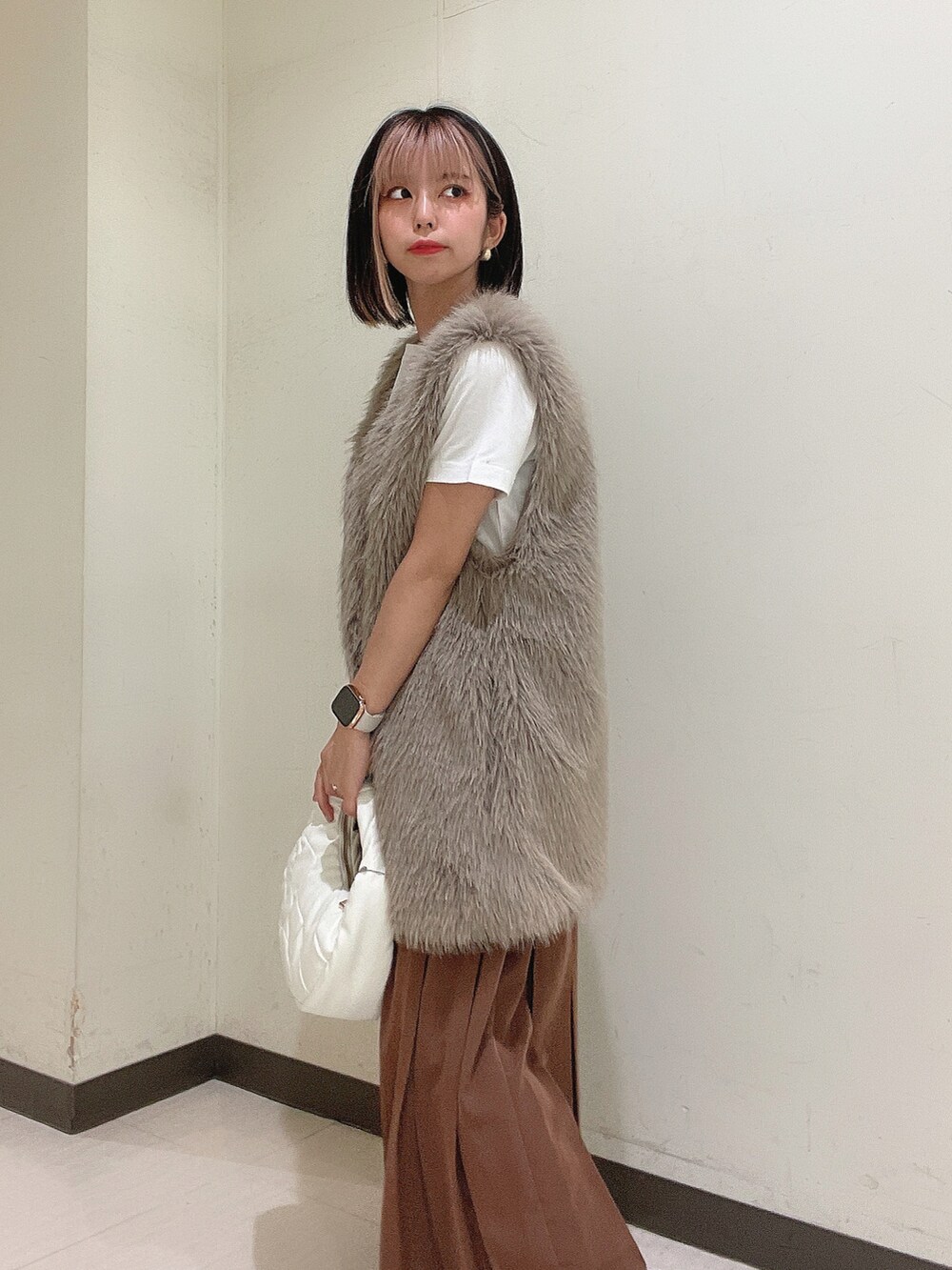 ホワイト系のショルダーバッグ、ブラック系のブーツ、ブラウン系のスカートを着用したレディースの秋コーディネートの5枚目の写真