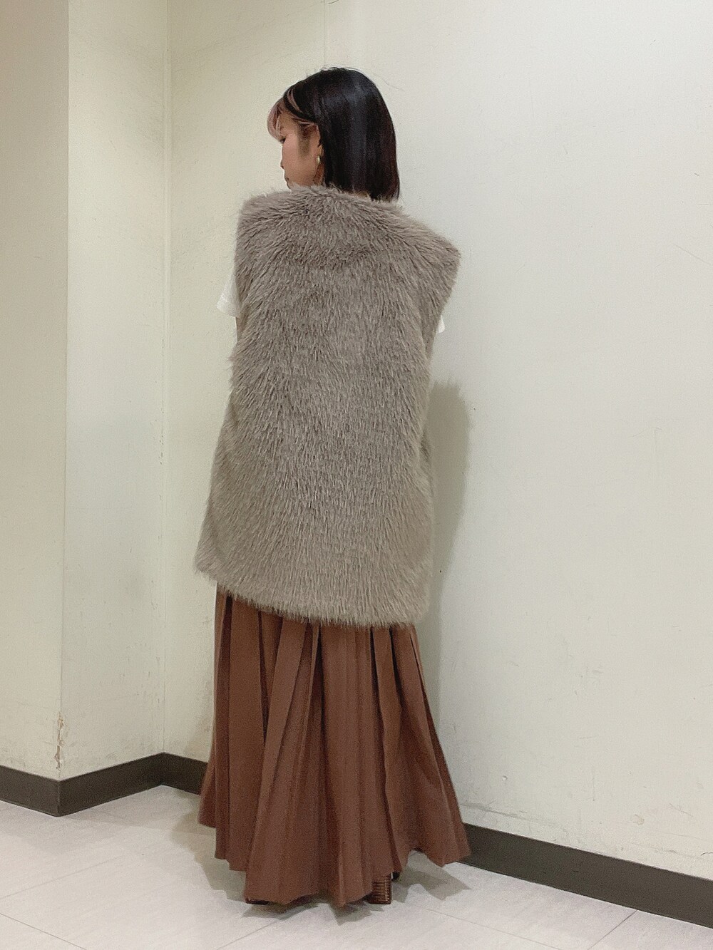 ホワイト系のショルダーバッグ、ブラック系のブーツ、ブラウン系のスカートを着用したレディースの秋コーディネートの2枚目の写真