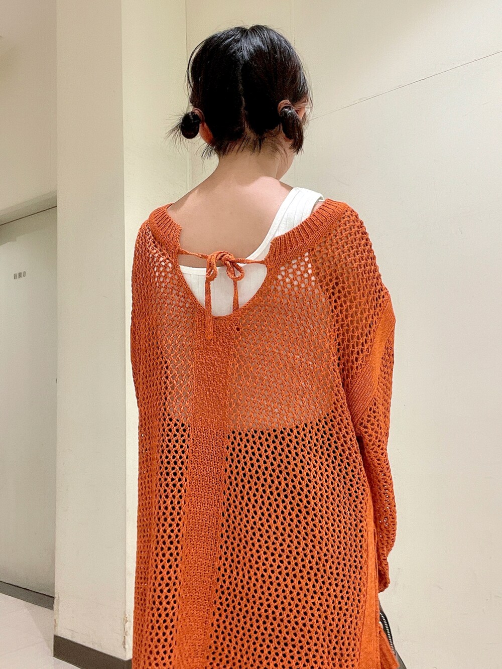 ブラック系のボストンバッグ、ブラック系のブーツ、オレンジ系のニット/セーターを着用したレディースの夏コーディネートの5枚目の写真