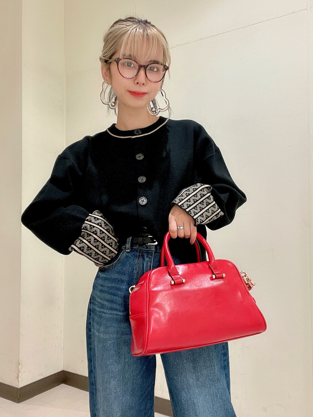ブラック系のカーディガン/ボレロ、レッド系のボストンバッグ、ブルー系のデニムパンツを着用したレディースの秋コーディネートの4枚目の写真