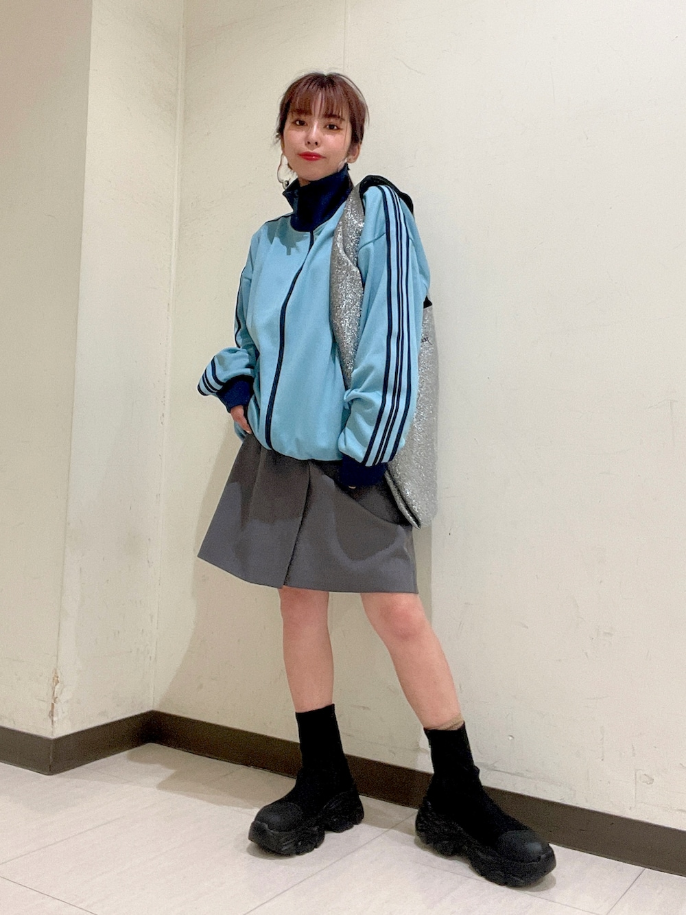 ブルー系のジャージ、シルバー系のトートバッグ、グレー系のスカートを着用したレディースの秋コーディネートの5枚目の写真