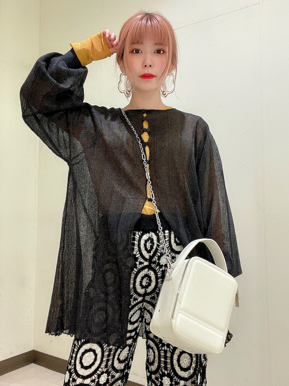 ブラック系のニット/セーター、イエロー系のTシャツ/カットソー、ホワイト系のショルダーバッグを着用したレディースの春コーディネートの5枚目の写真