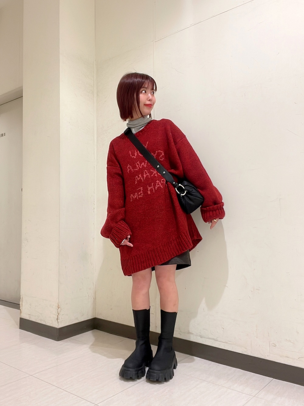 レッド系のニット/セーター、ブラック系のブーツ、ブラック系のショルダーバッグを着用したレディースの冬コーディネートの5枚目の写真