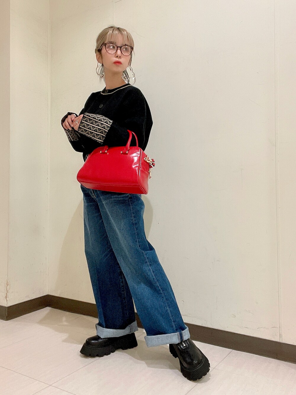 ブラック系のカーディガン/ボレロ、レッド系のボストンバッグ、ブルー系のデニムパンツを着用したレディースの秋コーディネートの2枚目の写真