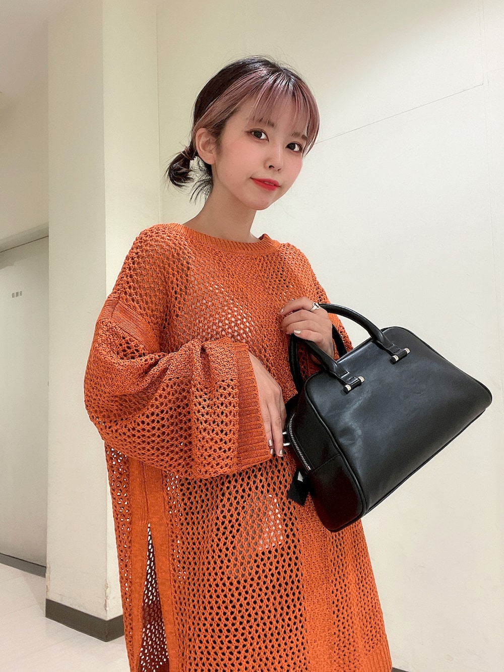 ブラック系のボストンバッグ、ブラック系のブーツ、オレンジ系のニット/セーターを着用したレディースの夏コーディネートの4枚目の写真