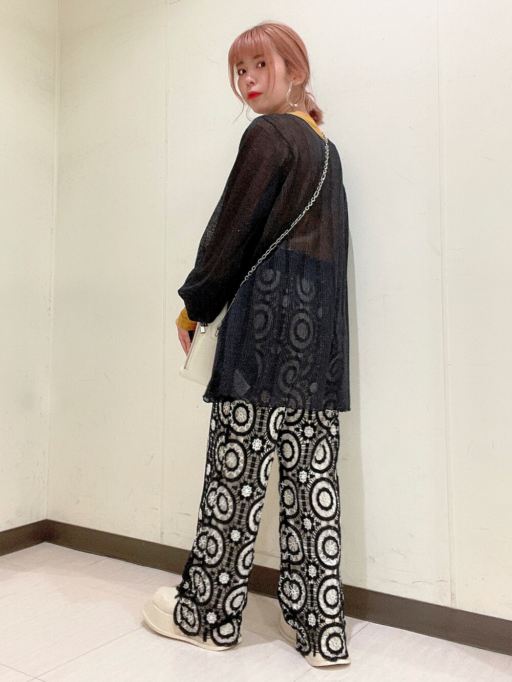 ブラック系のニット/セーター、イエロー系のTシャツ/カットソー、ホワイト系のショルダーバッグを着用したレディースの春コーディネートの2枚目の写真