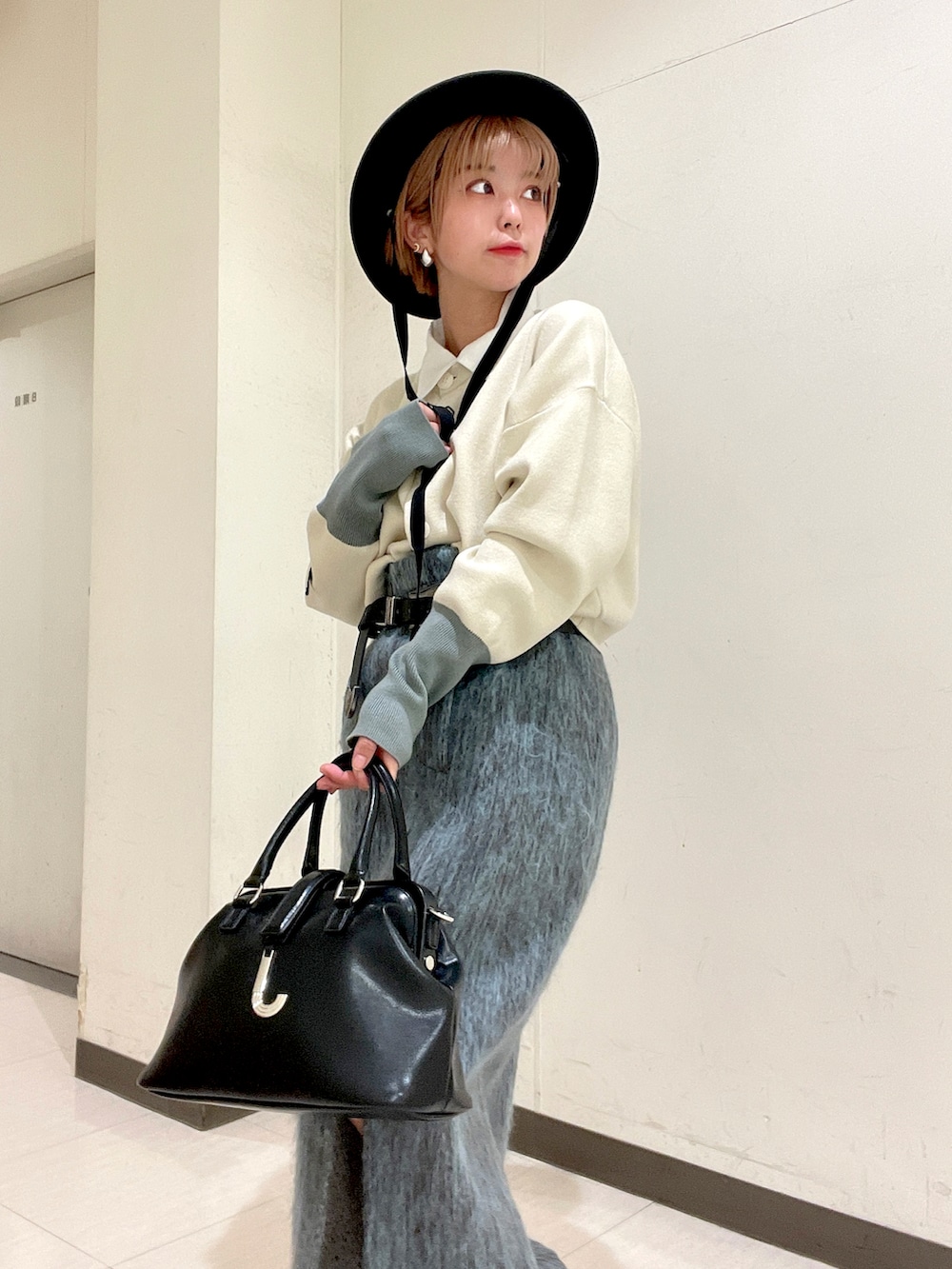 ホワイト系のカーディガン/ボレロ、ブルー系のスカート、ブラック系のパンプスを着用したレディースの冬コーディネートの4枚目の写真