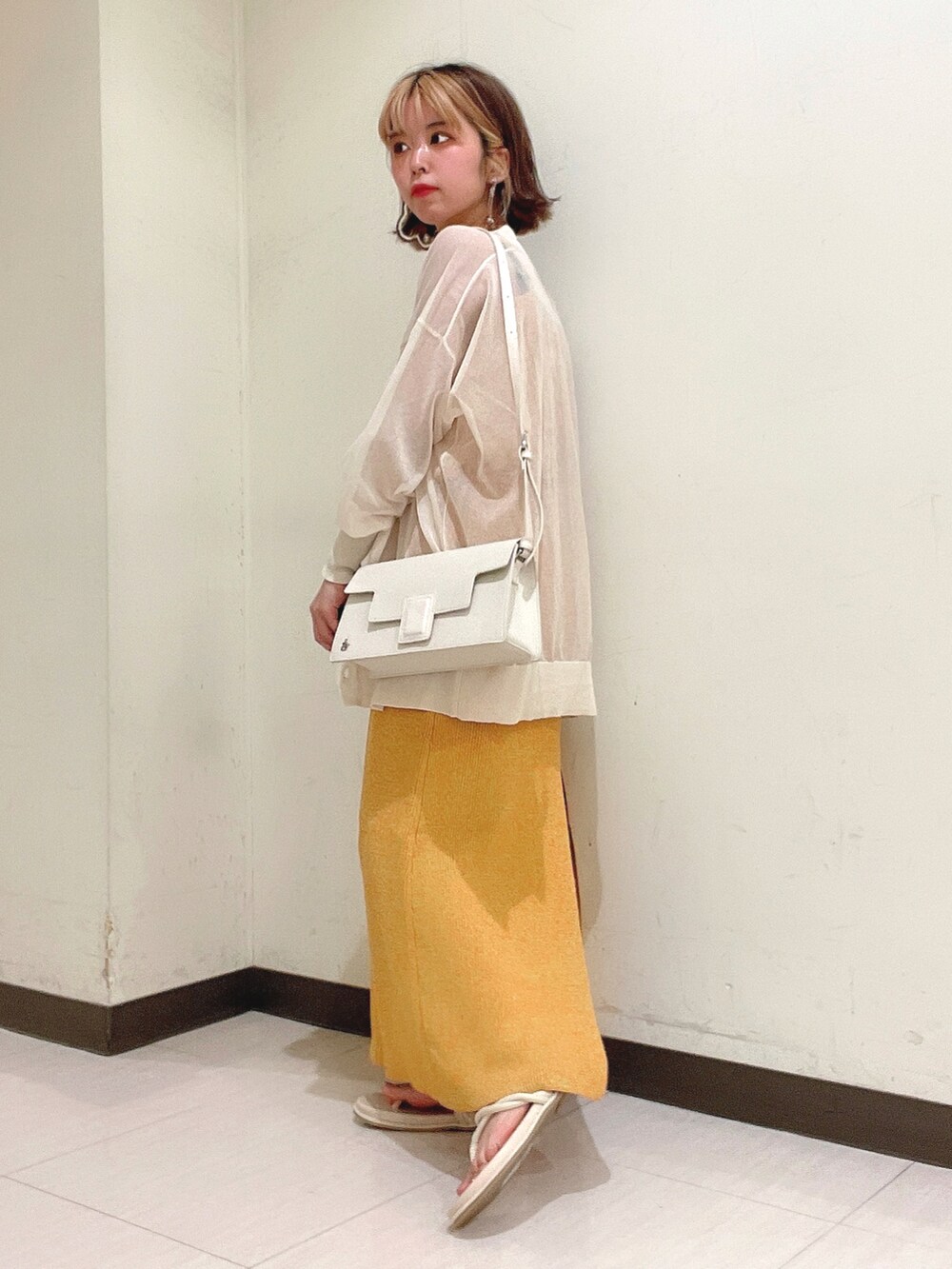 オレンジ系のワンピース、ホワイト系のショルダーバッグ、ベージュ系のカーディガン/ボレロを着用したレディースの夏コーディネートの3枚目の写真