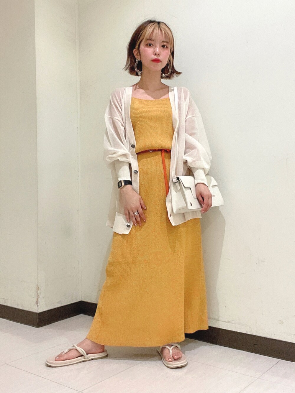 オレンジ系のワンピース、ホワイト系のショルダーバッグ、ベージュ系のカーディガン/ボレロを着用したレディースの夏コーディネートの2枚目の写真