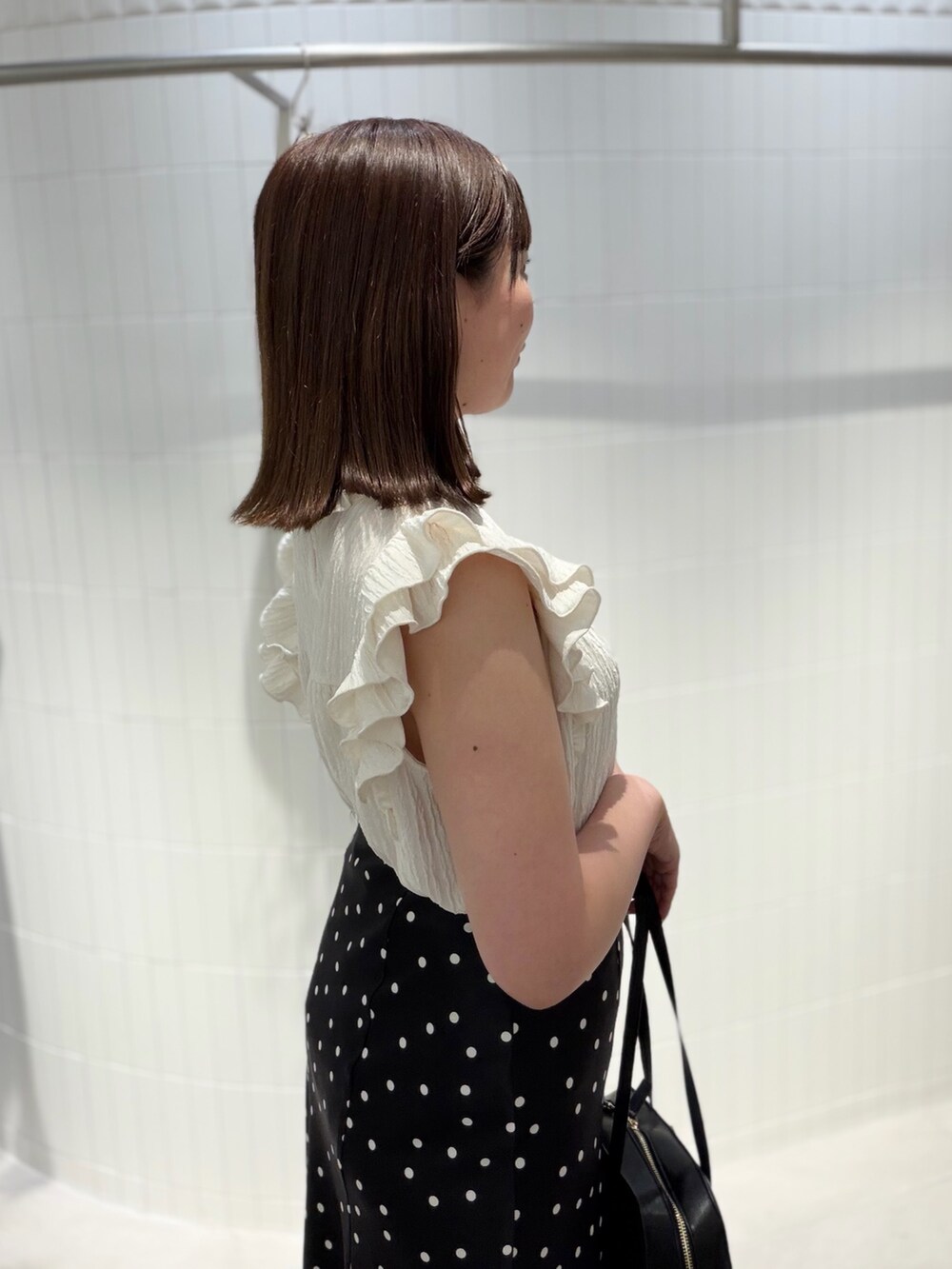 ブラック系のスカート、ホワイト系のTシャツ/カットソー、ブラック系のボストンバッグを着用したレディースの夏コーディネートの5枚目の写真
