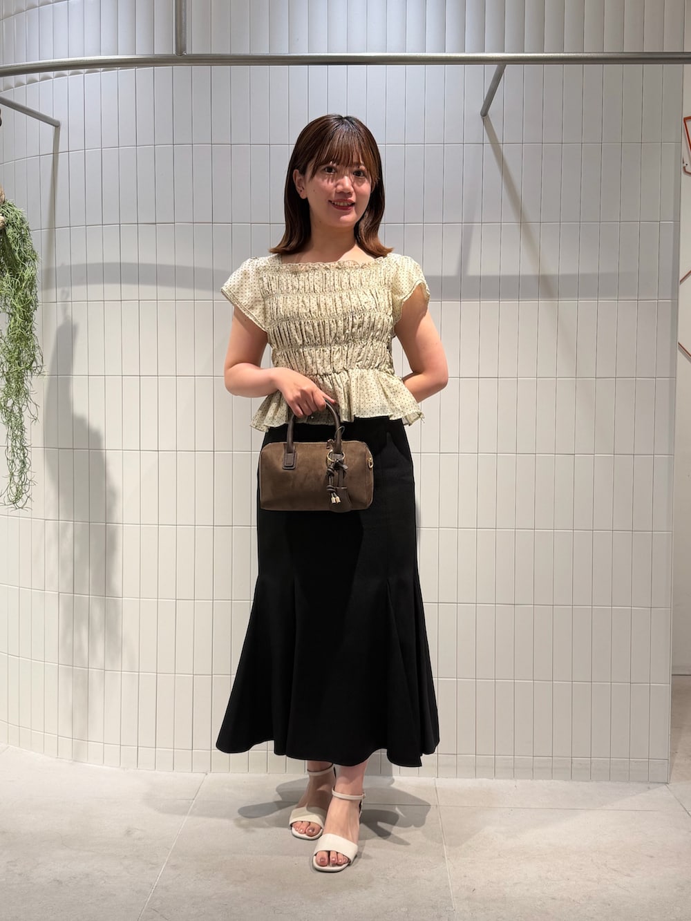 ブラック系のスカート、ベージュ系のシャツ/ブラウス、ブラウン系のボストンバッグを着用したレディースの夏コーディネートの2枚目の写真