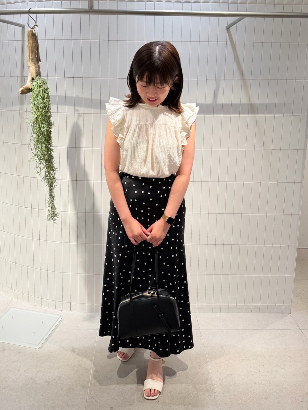 ブラック系のスカート、ホワイト系のTシャツ/カットソー、ブラック系のボストンバッグを着用したレディースの夏コーディネートの3枚目の写真