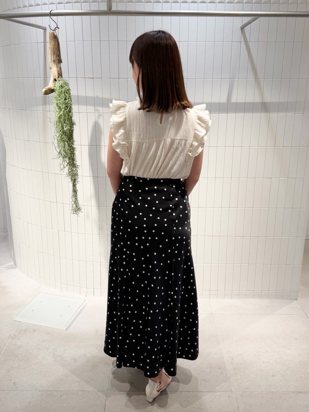 ブラック系のスカート、ホワイト系のTシャツ/カットソー、ブラック系のボストンバッグを着用したレディースの夏コーディネートの4枚目の写真