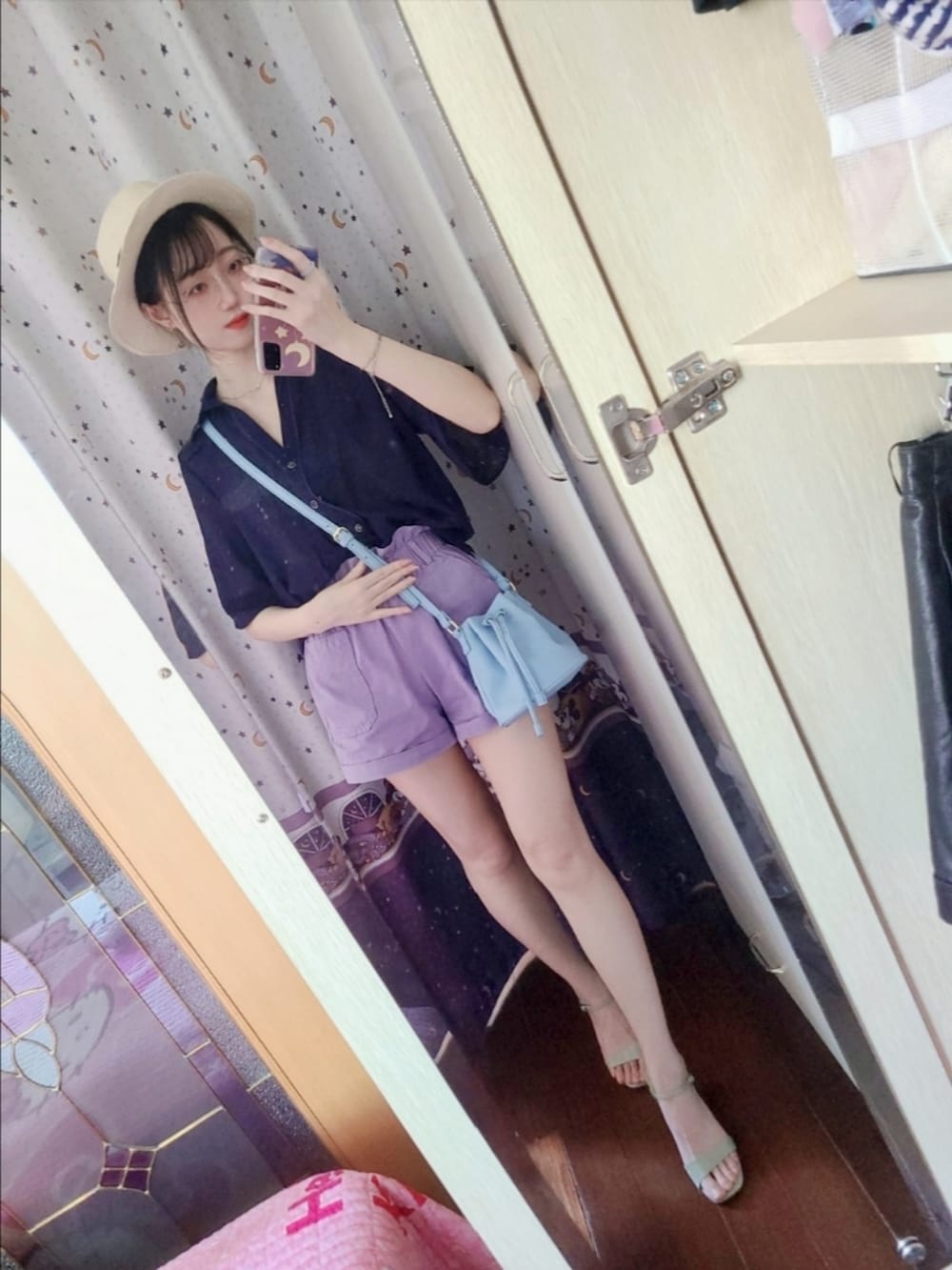 パープル系のカーゴパンツ、ブルー系のドラムバッグ、グリーン系のサンダルを着用したレディースの夏コーディネートの2枚目の写真