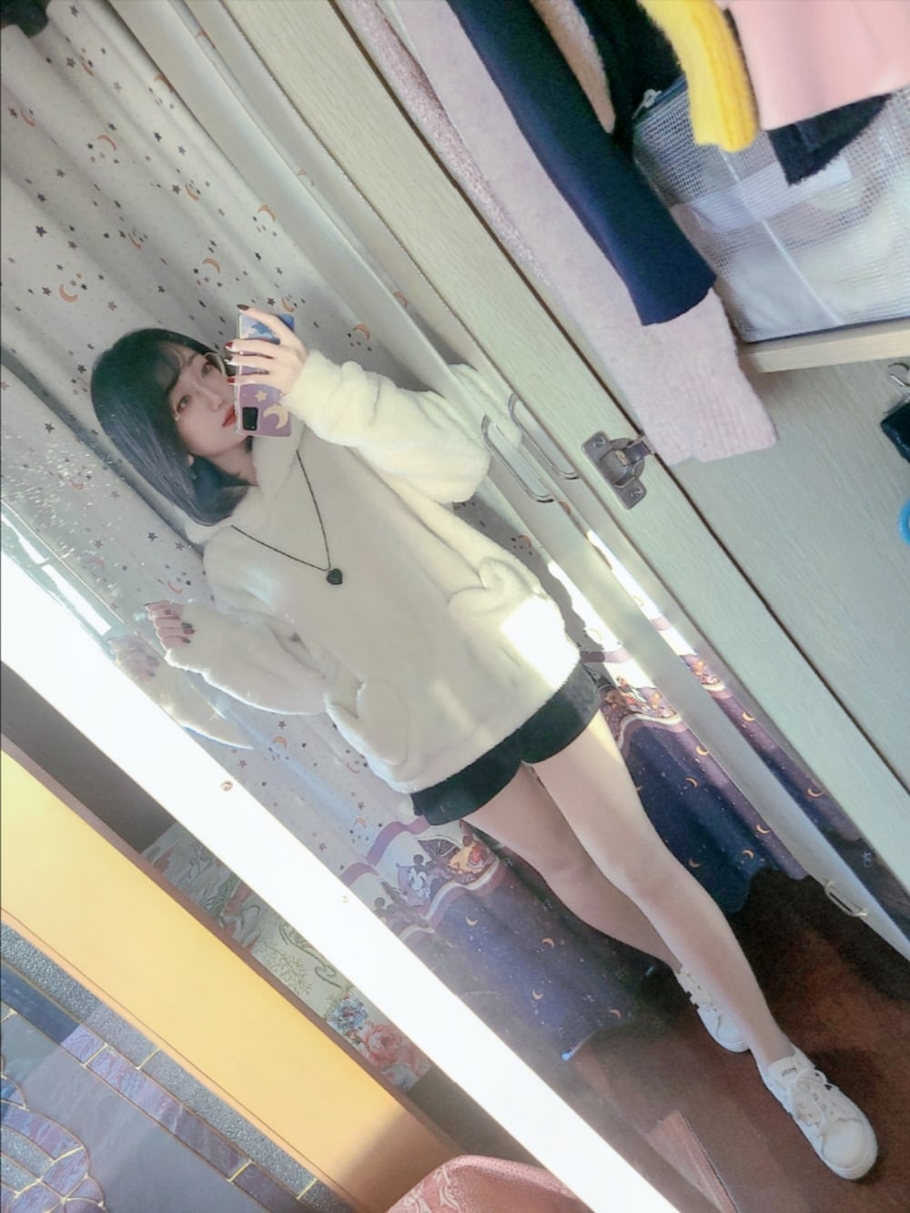 ホワイト系のパーカー、ブラック系のカーゴパンツ、ホワイト系のスニーカーを着用したレディースの冬コーディネートの2枚目の写真