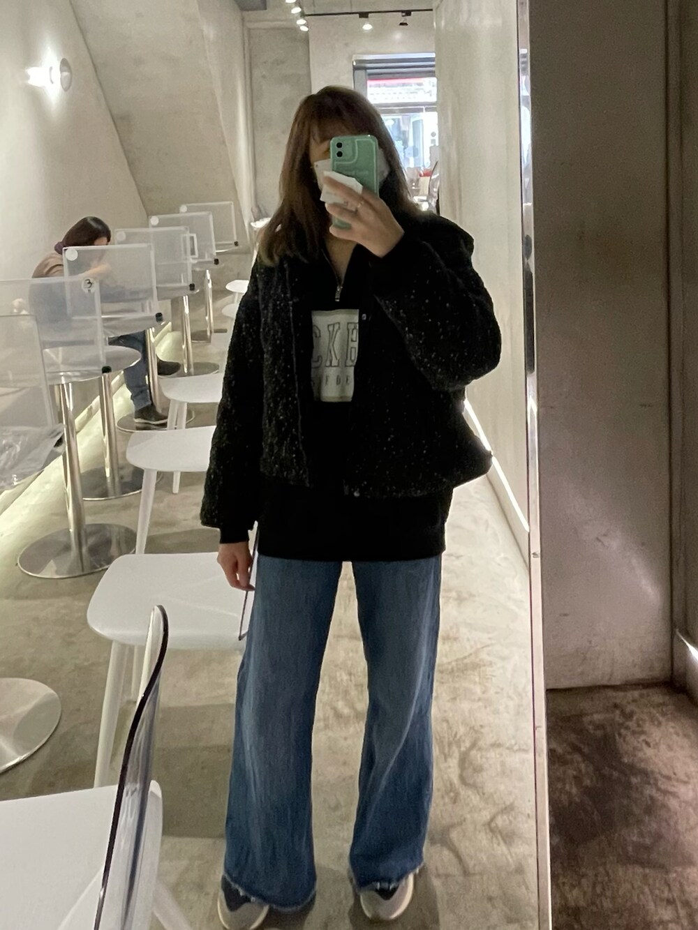 ブラック系のポロシャツ、ホワイト系のスニーカー、ブラック系のジャケット/アウターを着用したレディースの冬コーディネートの2枚目の写真