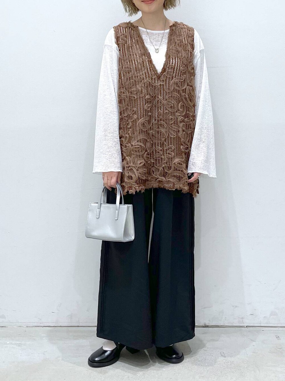 ブラウン系のベスト、グレー系のショルダーバッグ、ホワイト系のTシャツ/カットソーを着用したレディースの春コーディネートの3枚目の写真