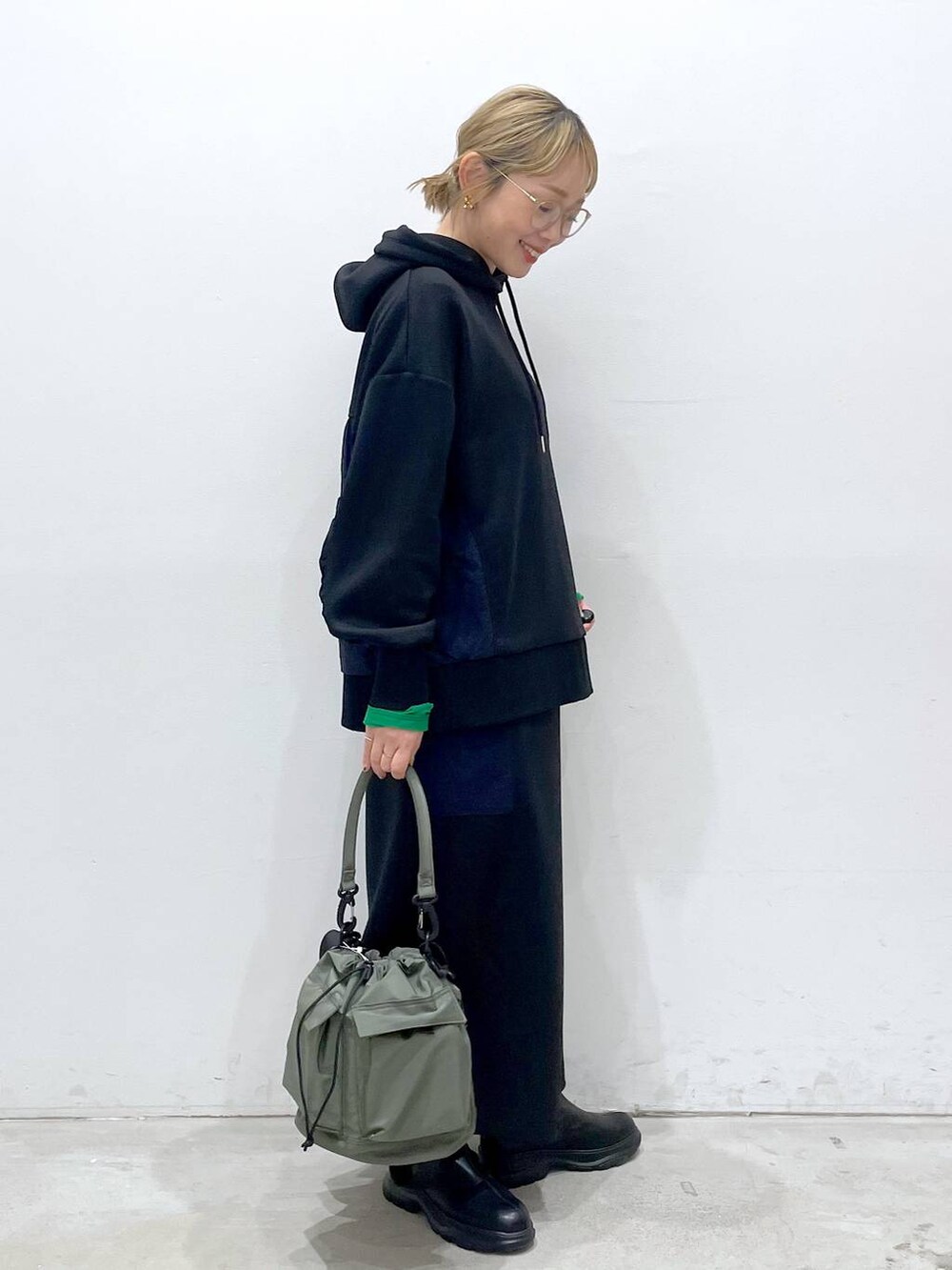 グリーン系のショルダーバッグ、ブラック系のTシャツ/カットソー、ブラック系のブーツを着用したレディースの冬コーディネートの2枚目の写真