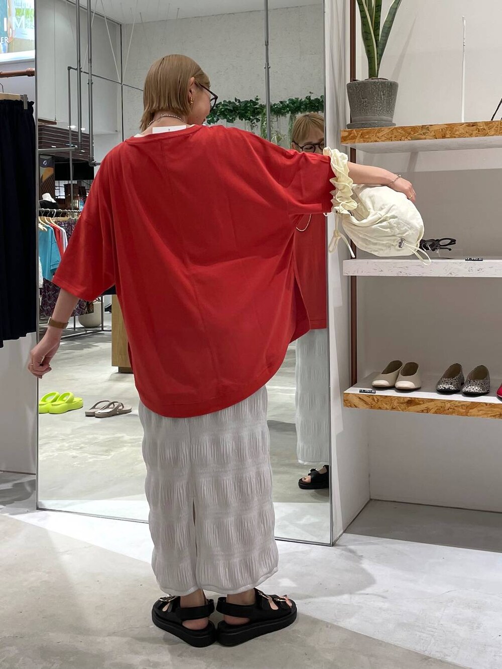 ホワイト系のショルダーバッグ、ブラック系のサンダル、レッド系のTシャツ/カットソーを着用したレディースの夏コーディネートの3枚目の写真