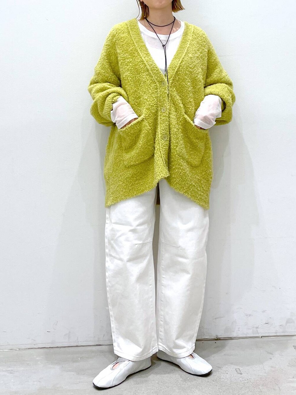 ホワイト系のデニムパンツ、シルバー系のバレエシューズ、イエロー系のカーディガン/ボレロを着用したレディースの冬コーディネートの4枚目の写真