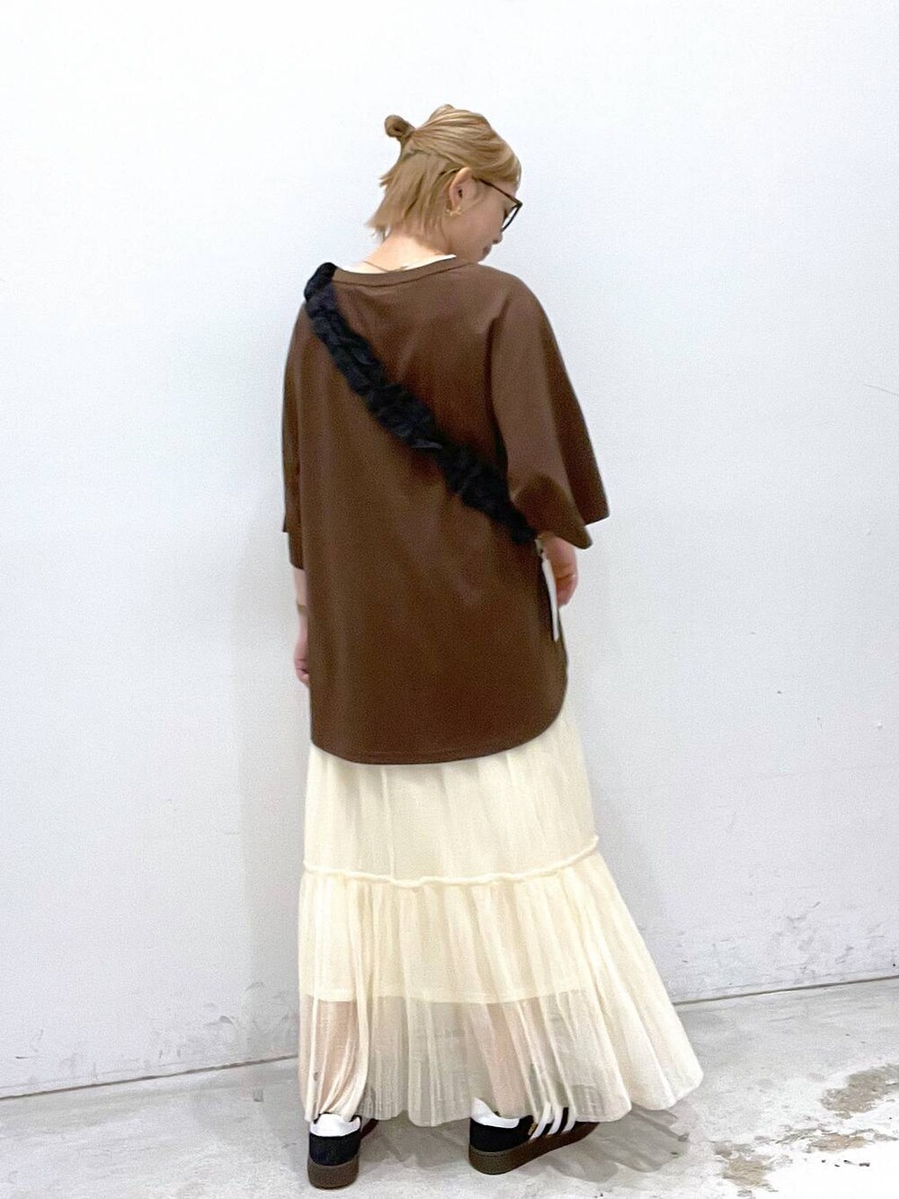 ホワイト系のタンクトップ、ブラック系のスニーカー、ブラック系のスマホグッズを着用したレディースの夏コーディネートの3枚目の写真