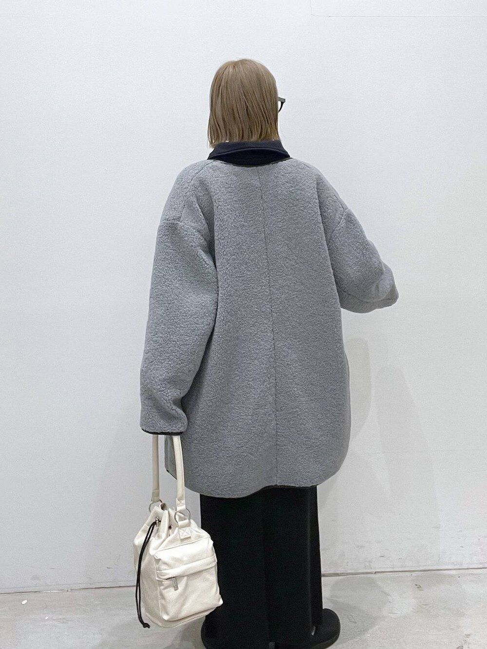 ブラック系のスカート、グレー系のその他アウター、ホワイト系のショルダーバッグを着用したレディースの秋コーディネートの3枚目の写真