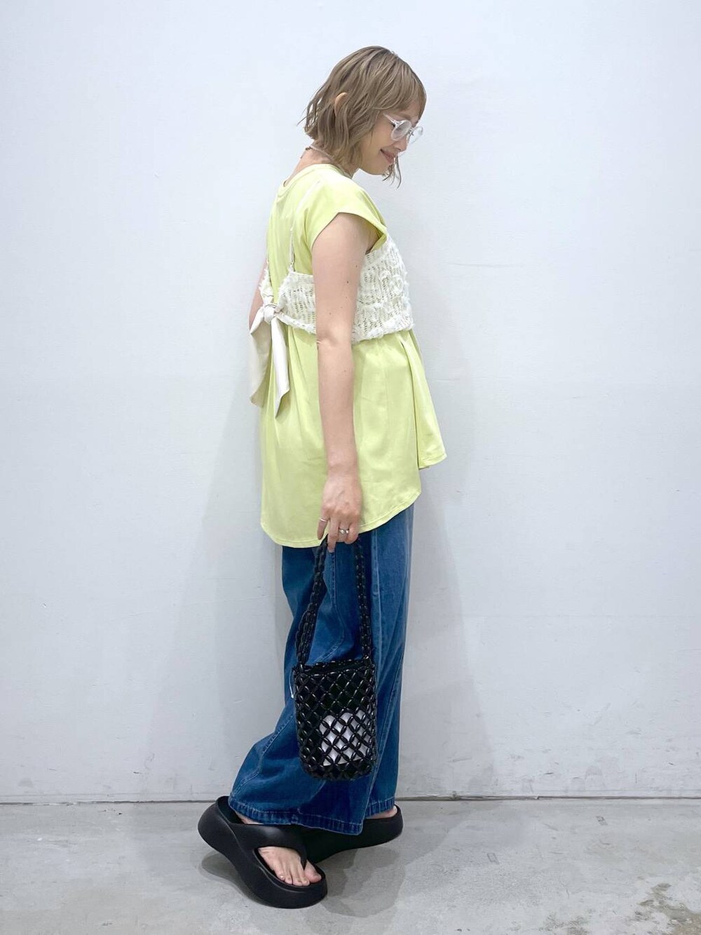 ブルー系のデニムパンツ、グリーン系のTシャツ/カットソー、ブラック系のサンダルを着用したレディースの夏コーディネートの2枚目の写真