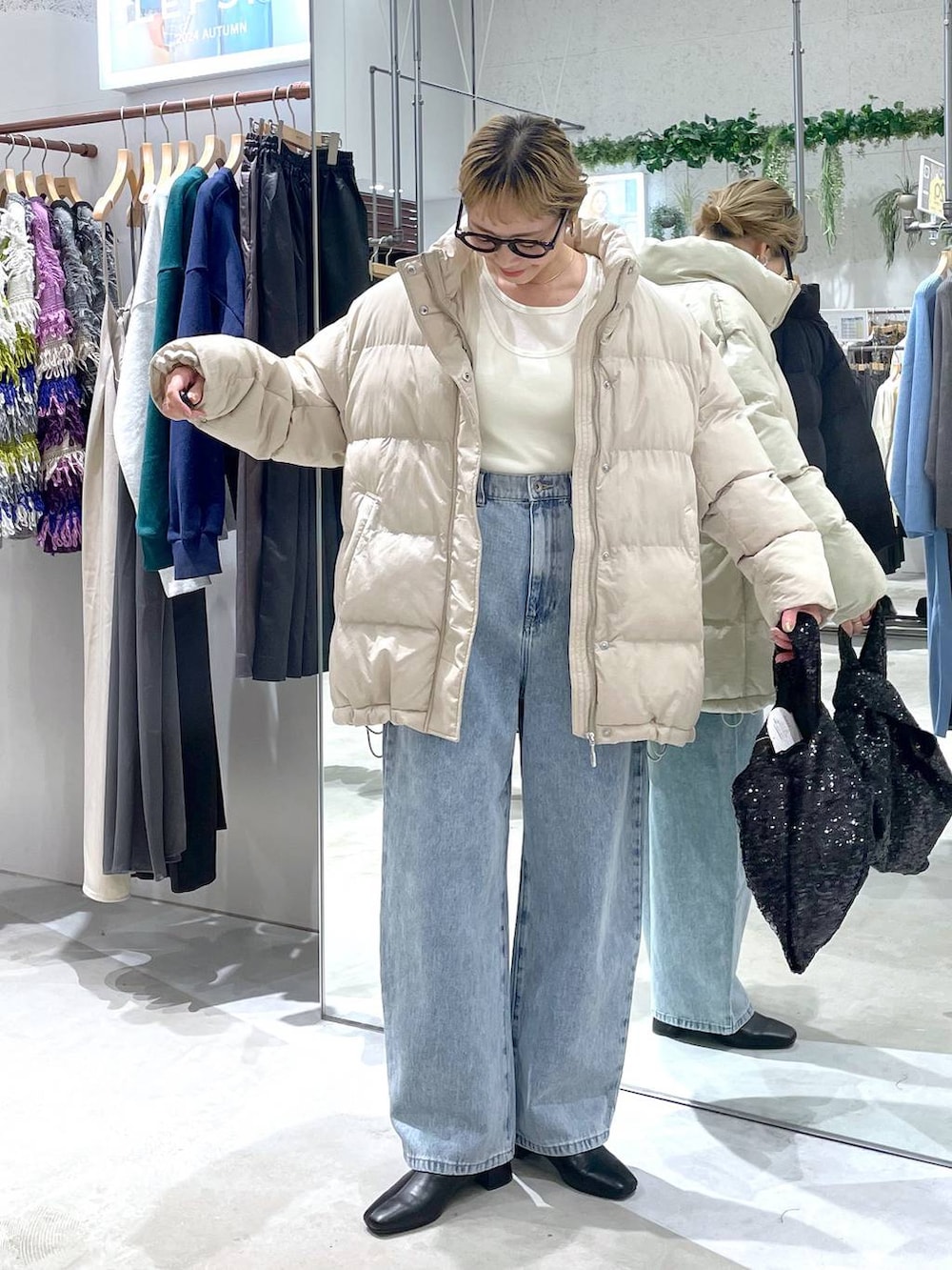 ベージュ系のダウンジャケット/コート、ブラック系のブーツ、ブルー系のデニムパンツを着用したレディースの秋コーディネートの4枚目の写真