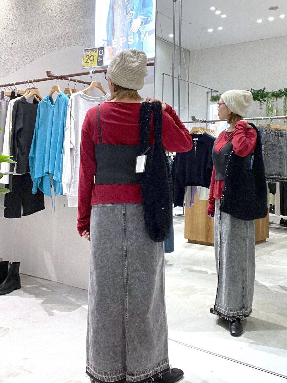 ブラック系のショルダーバッグ、グレー系のデニムスカート、ブラック系のブーツを着用したレディースの秋コーディネートの2枚目の写真