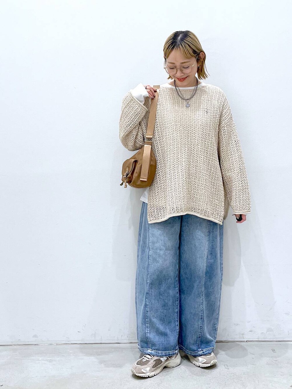 ホワイト系のニット/セーター、ブルー系のデニムパンツ、ホワイト系のTシャツ/カットソーを着用したレディースの春コーディネートの4枚目の写真