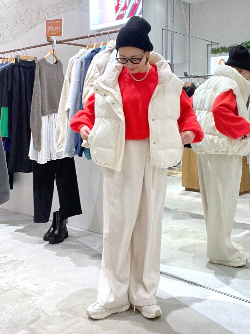 ホワイト系のダウンベスト、レッド系のニット/セーター、ホワイト系のその他パンツを着用したレディースの秋コーディネートの4枚目の写真