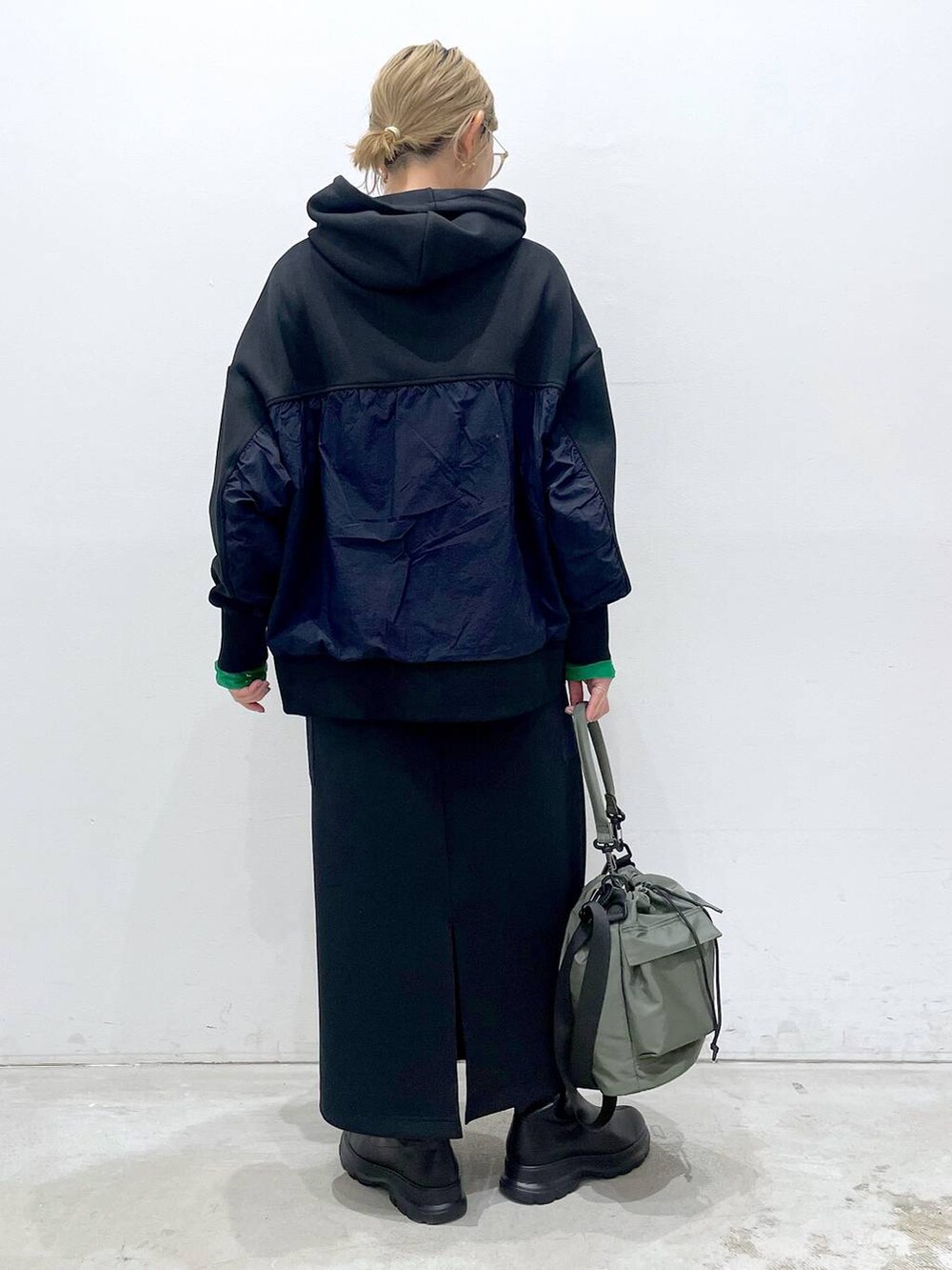 グリーン系のショルダーバッグ、ブラック系のTシャツ/カットソー、ブラック系のブーツを着用したレディースの冬コーディネートの3枚目の写真