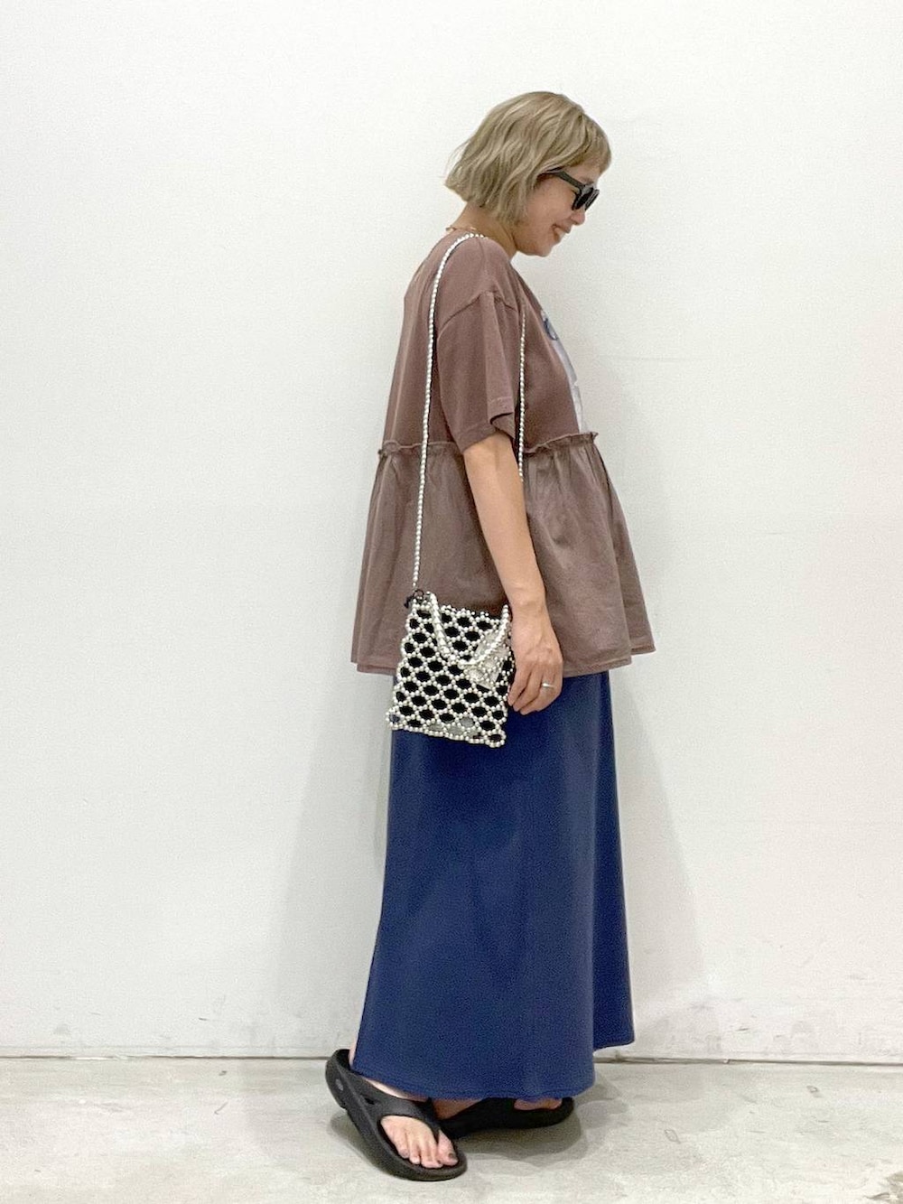 ブルー系のスカート、ブラウン系のTシャツ/カットソー、シルバー系のショルダーバッグを着用したレディースの夏コーディネートの2枚目の写真