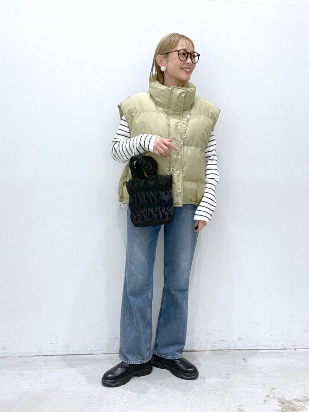ベージュ系のダウンベスト、ブルー系のデニムパンツ、ブラック系のブーツを着用したレディースの冬コーディネートの4枚目の写真