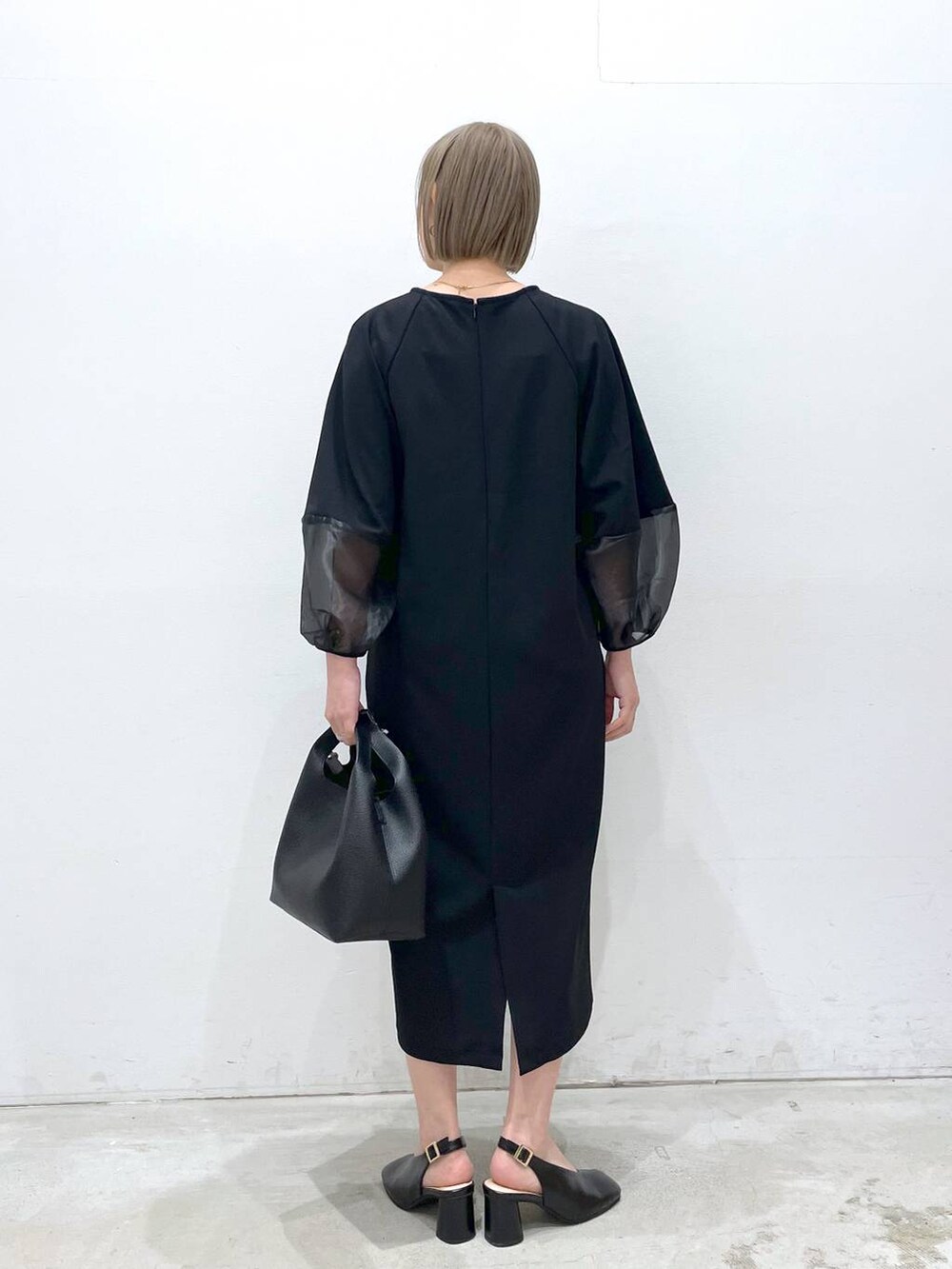 ブラック系のワンピース、ブラック系のパンプス、ブラック系のショルダーバッグを着用したレディースの冬コーディネートの3枚目の写真