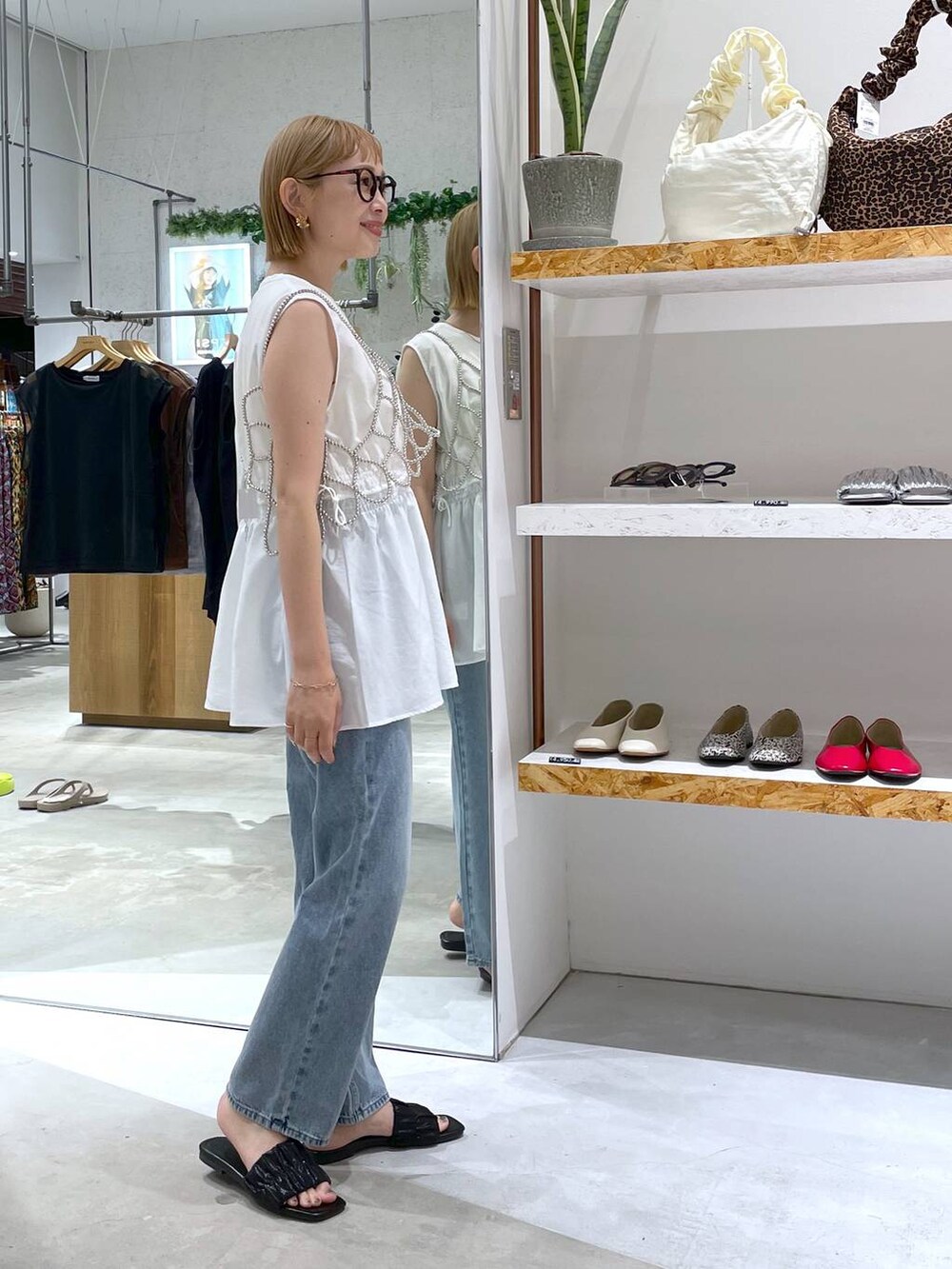 シルバー系のベスト、ホワイト系のタンクトップ、ブルー系のデニムパンツを着用したレディースの夏コーディネートの2枚目の写真