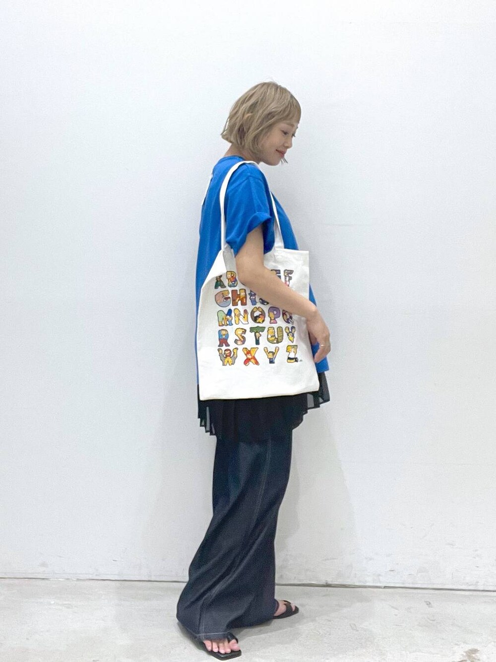 ブルー系のデニムパンツ、ブラック系のスカート、ブラック系のサンダルを着用したレディースの夏コーディネートの2枚目の写真