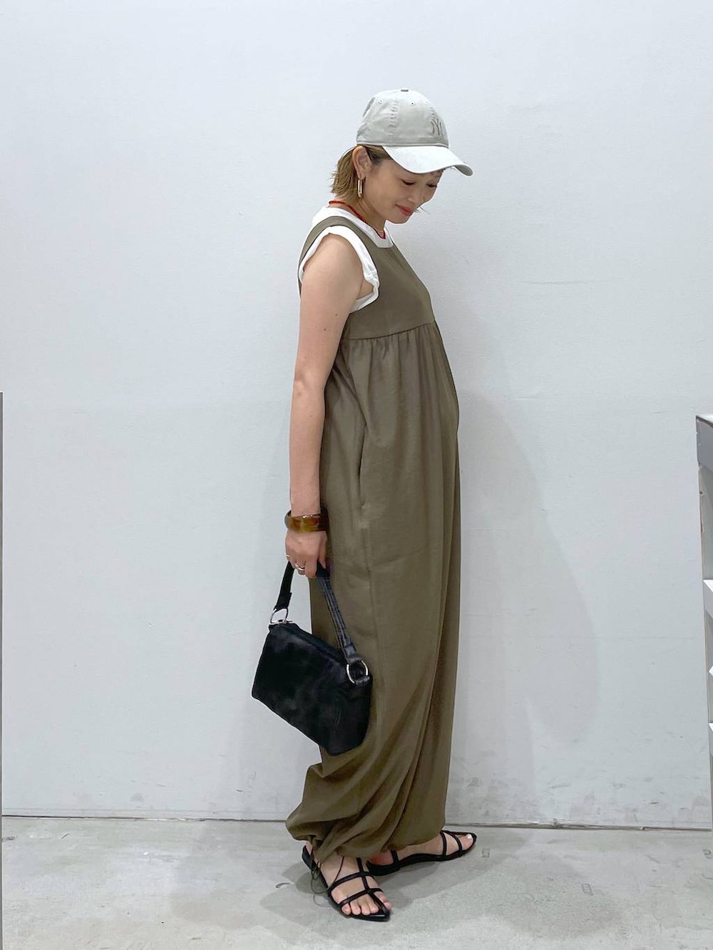 ブラック系のサンダル、イエロー系のつなぎ/オールインワン、ブラック系のハンドバッグを着用したレディースの夏コーディネートの2枚目の写真