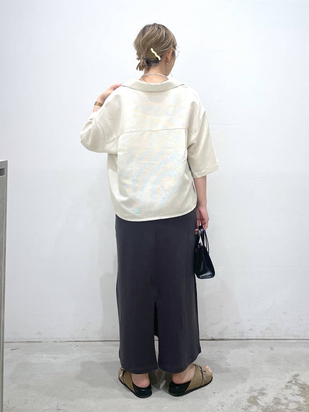 ブラック系のショルダーバッグ、グレー系のスカート、ベージュ系のシャツ/ブラウスを着用したレディースの夏コーディネートの3枚目の写真