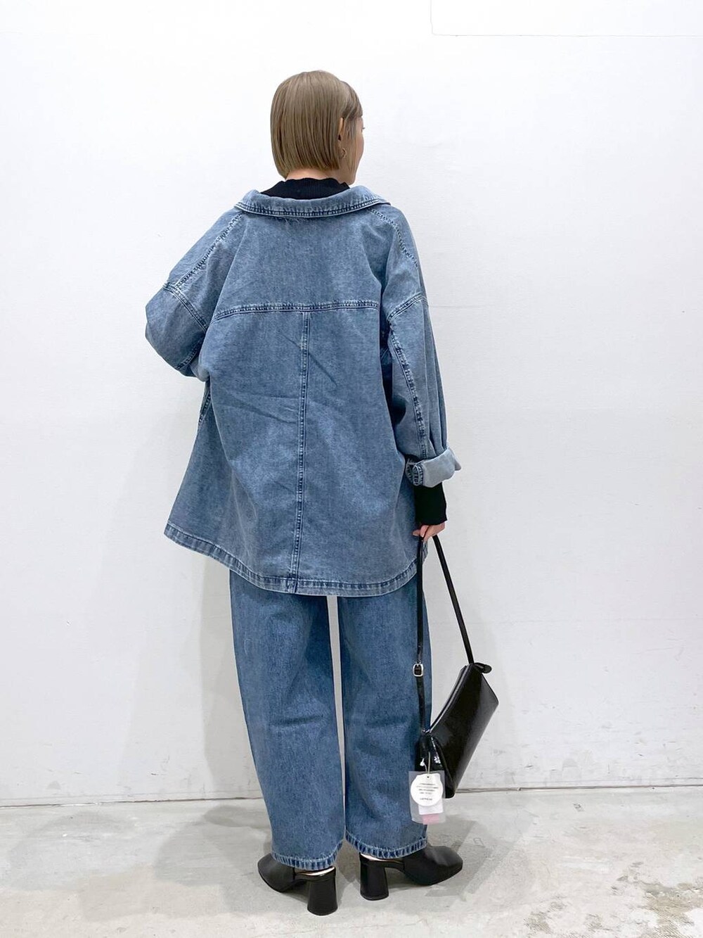 ブラック系のニット/セーター、ブルー系のデニムパンツ、ブラック系のパンプスを着用したレディースの冬コーディネートの3枚目の写真